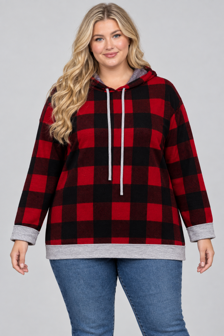 Studio front view of a new plus-size blonde model wearing the red-and-black plaid hoodie and blue jeans