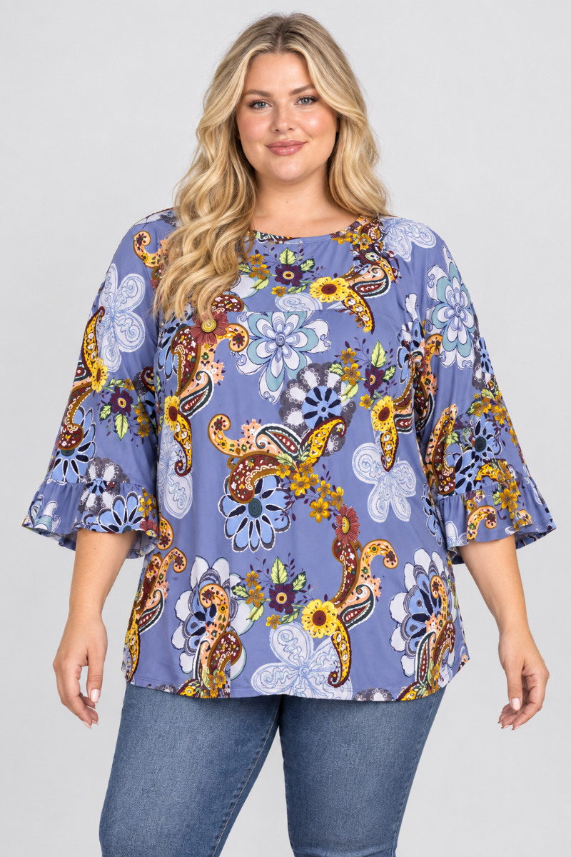 Studio front view of a plus-size blonde model wearing the periwinkle floral-paisley blouse and blue jeans
