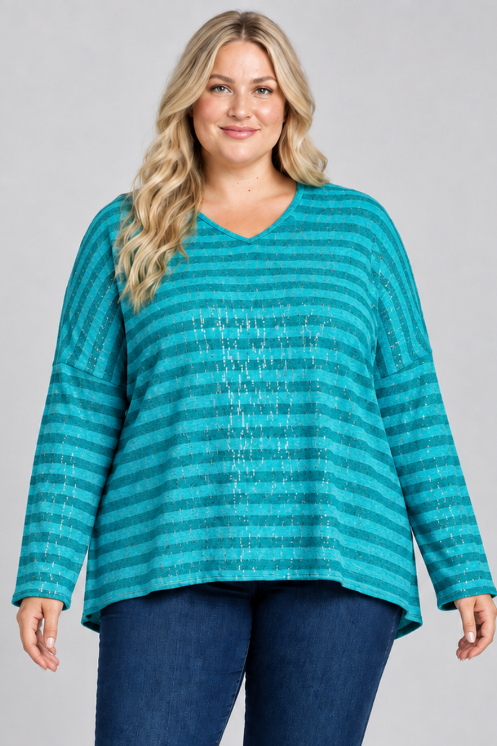 Studio front view of blonde model in a loose teal striped top and dark jeans