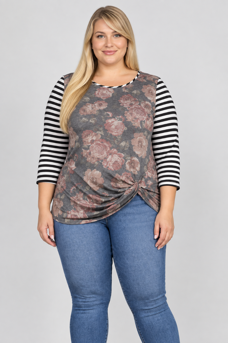 Studio front view of blonde model in charcoal floral top with black-and-white striped sleeves and blue jeans