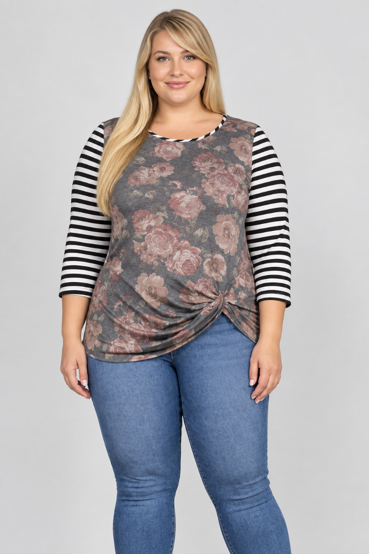 Studio front view of blonde model in charcoal floral top with black-and-white striped sleeves and blue jeans