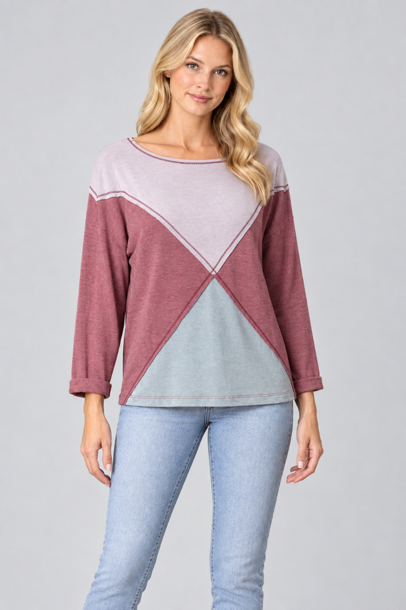 Studio front view of the blonde model wearing the lilac, mauve, and pale-blue geometric color-block top