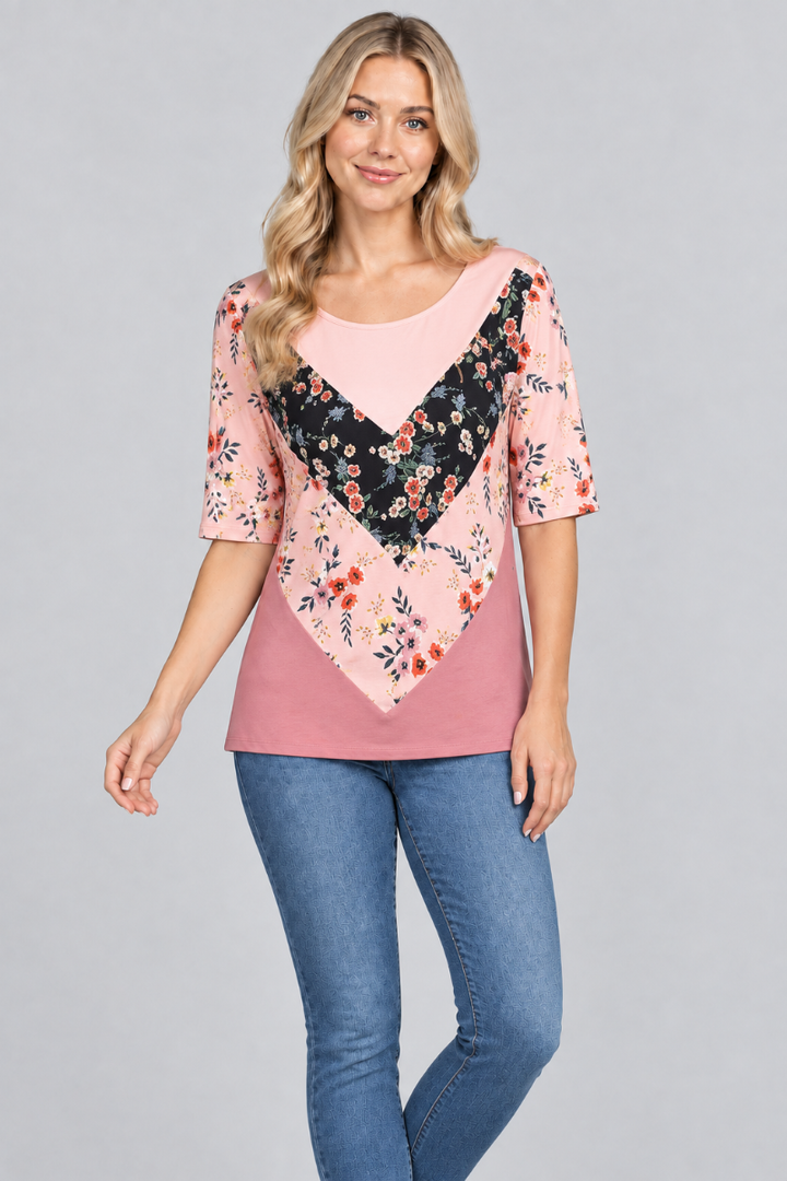 Studio front view of the blonde model wearing the pink floral color-block top and denim jeans