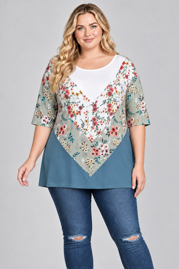 Studio front view of the blonde plus-size model wearing the white, sage floral, and teal color-block tunic