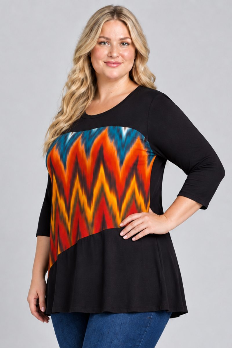 Studio side view of blonde model in black tunic with colorful geometric panel and dark jeans