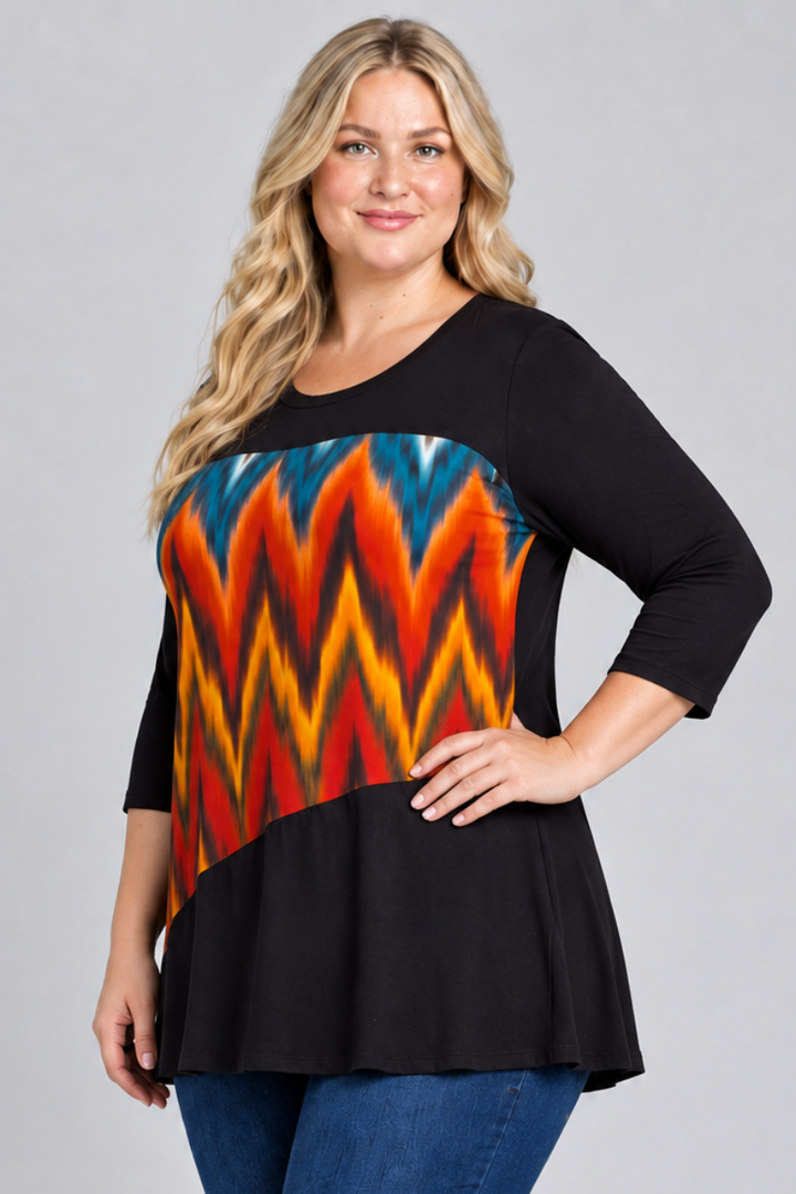 Studio side view of blonde model in black tunic with colorful geometric panel and dark jeans