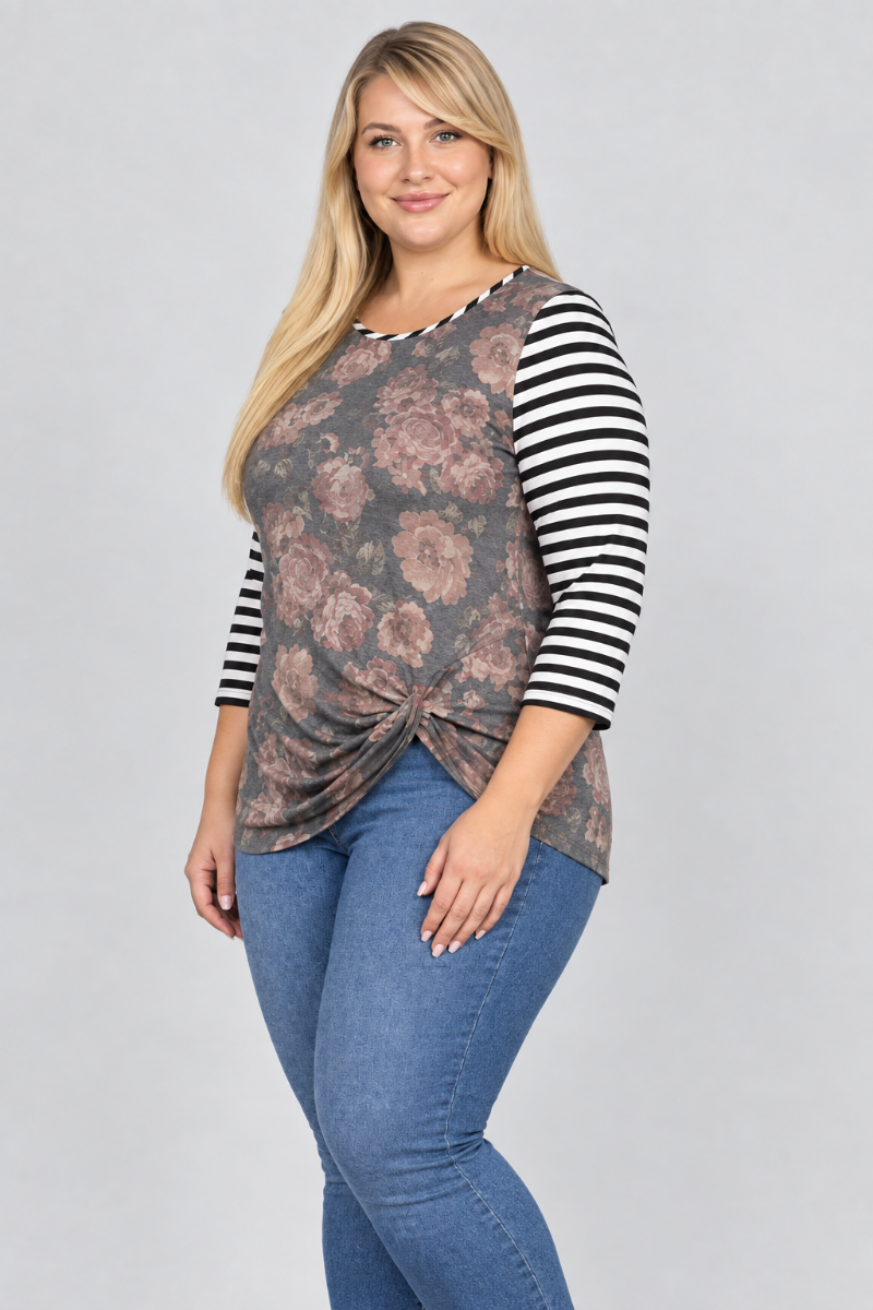 Studio side view of blonde model in charcoal floral top with black-and-white striped sleeves and blue jeans
