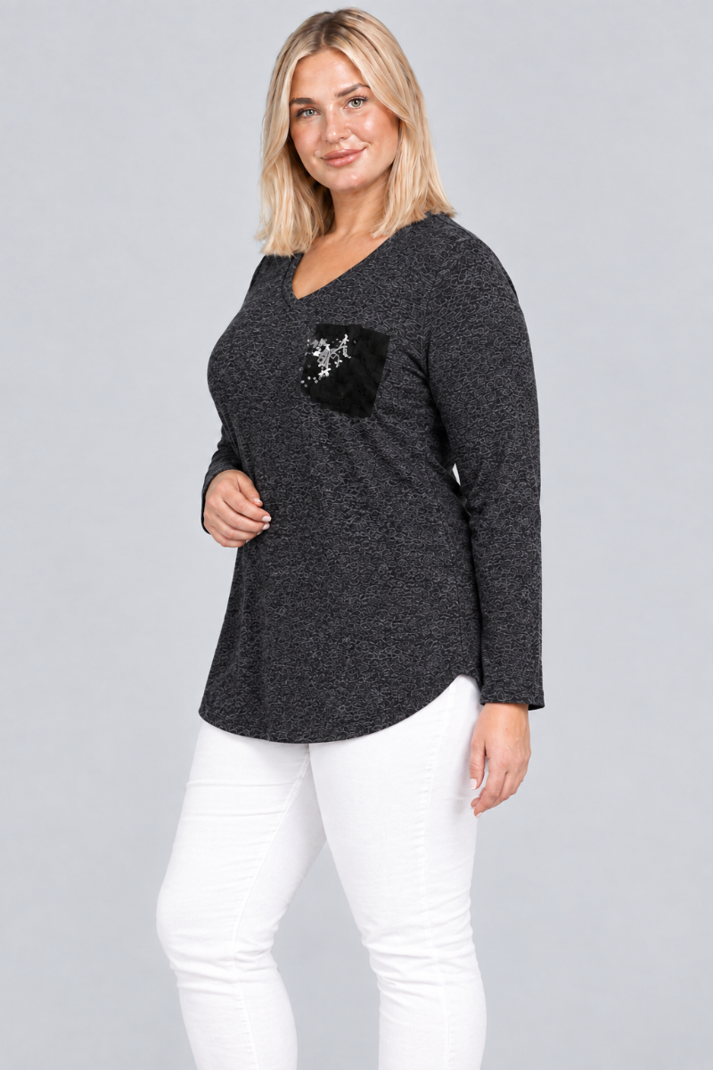 Studio side view of blonde model in charcoal heather V-neck tunic with black embellished pocket and white pants