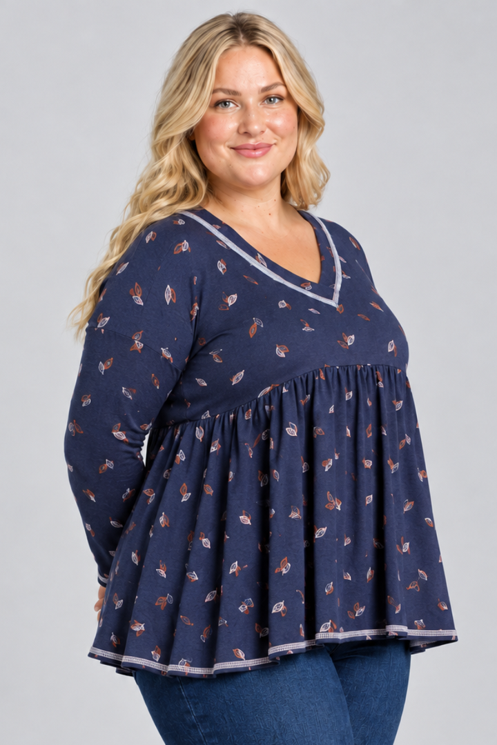 Studio side view of blonde model in navy leaf-print blouse with contrast trim and dark jeans