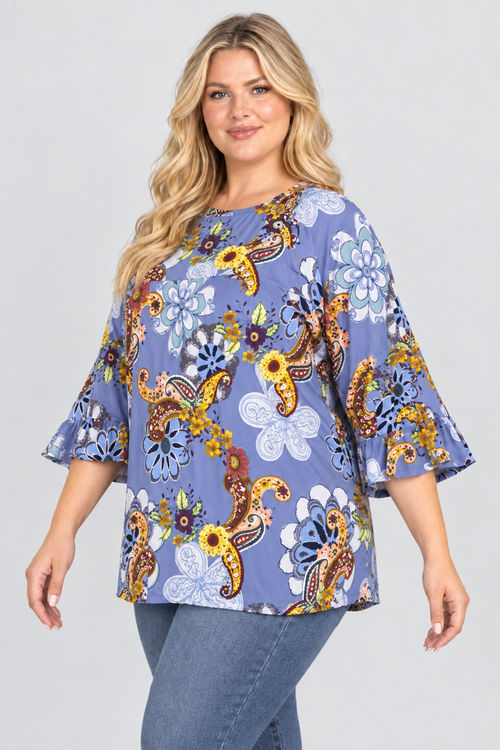 Three-quarter studio view of a plus-size blonde model wearing the periwinkle floral-paisley blouse and blue jeans