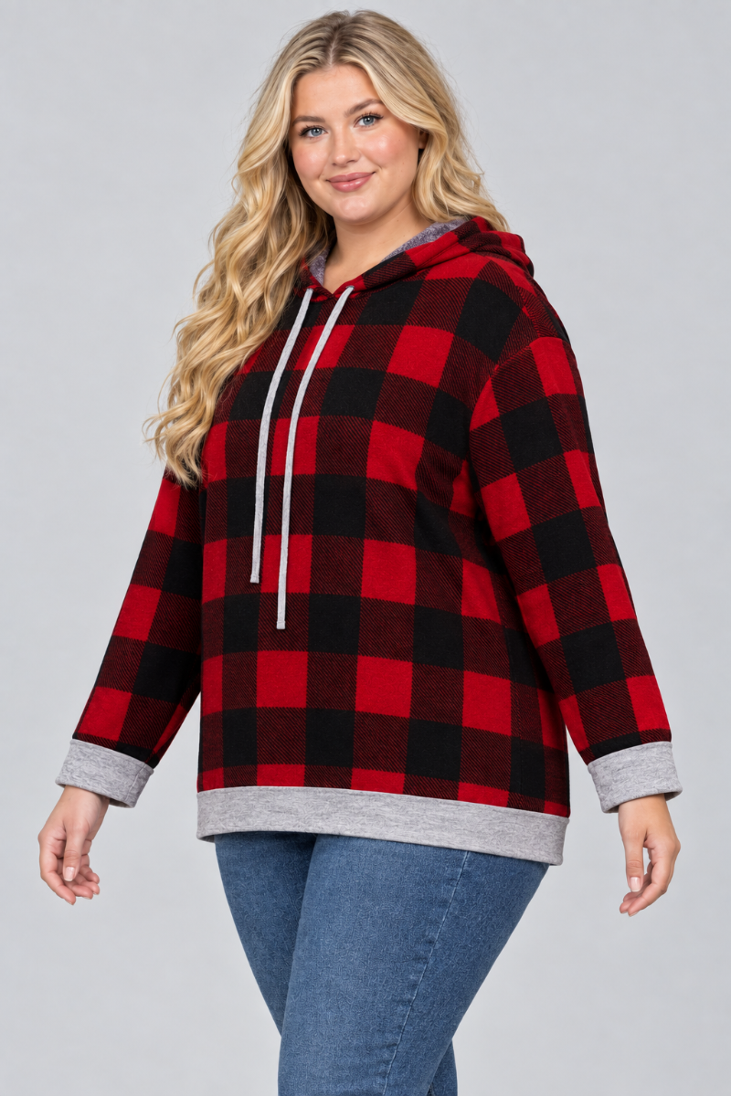 Three-quarter studio view of a plus-size blonde model wearing the red-and-black plaid hoodie and blue jeans