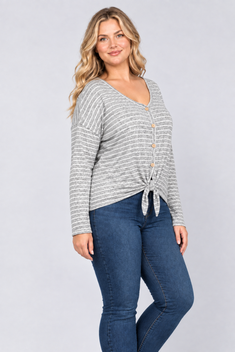 Three-quarter studio view of the blonde curvy XL model wearing the gray striped tie-front top and blue jeans