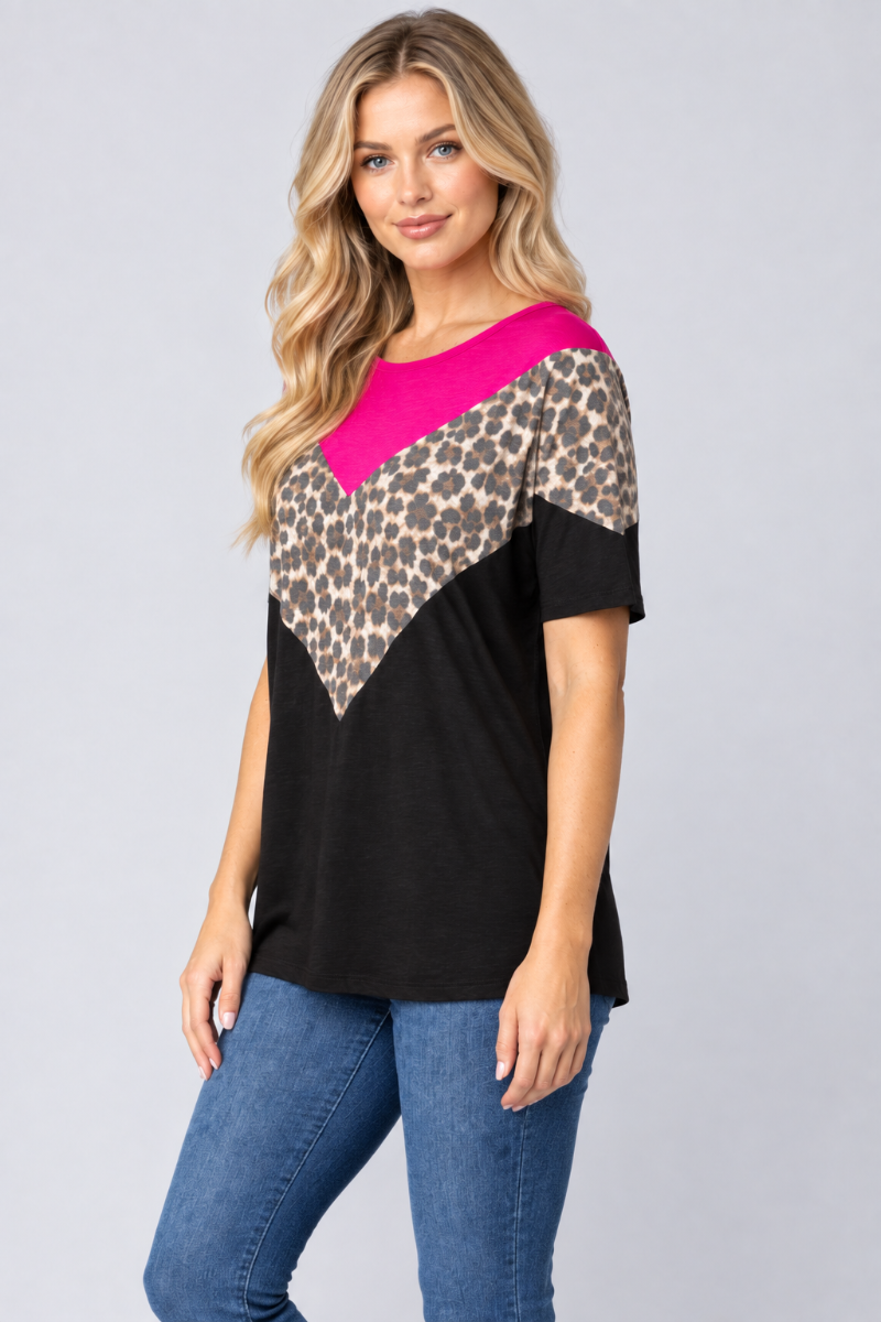 Three-quarter studio view of the blonde model wearing the black, fuchsia, and leopard-print top with blue jeans