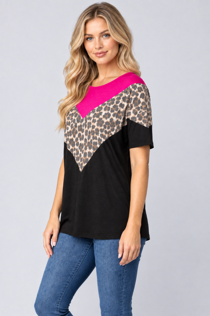 Three-quarter studio view of the blonde model wearing the black, fuchsia, and leopard-print top with blue jeans