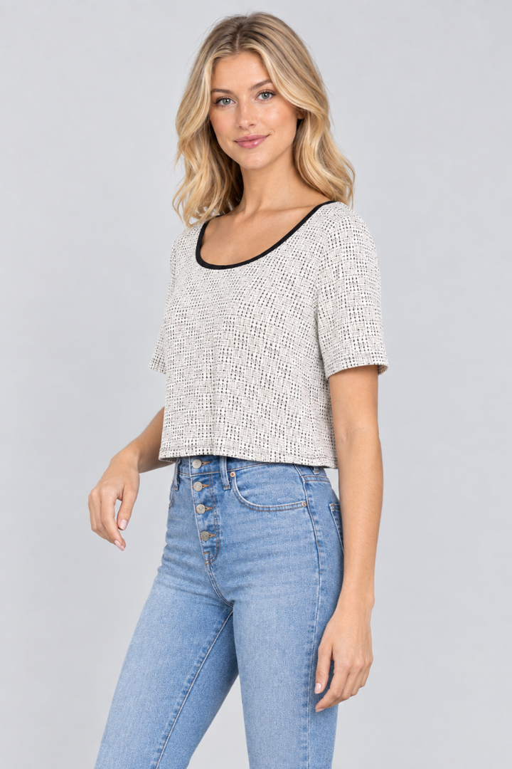 Three-quarter studio view of the blonde model wearing the ivory micro-print crop top and light-wash jeans