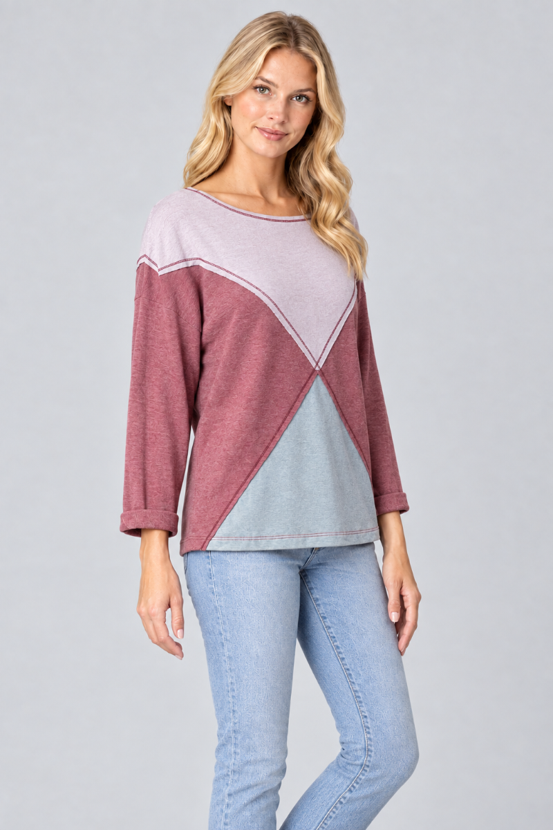 Three-quarter studio view of the blonde model wearing the lilac, mauve, and pale-blue geometric top
