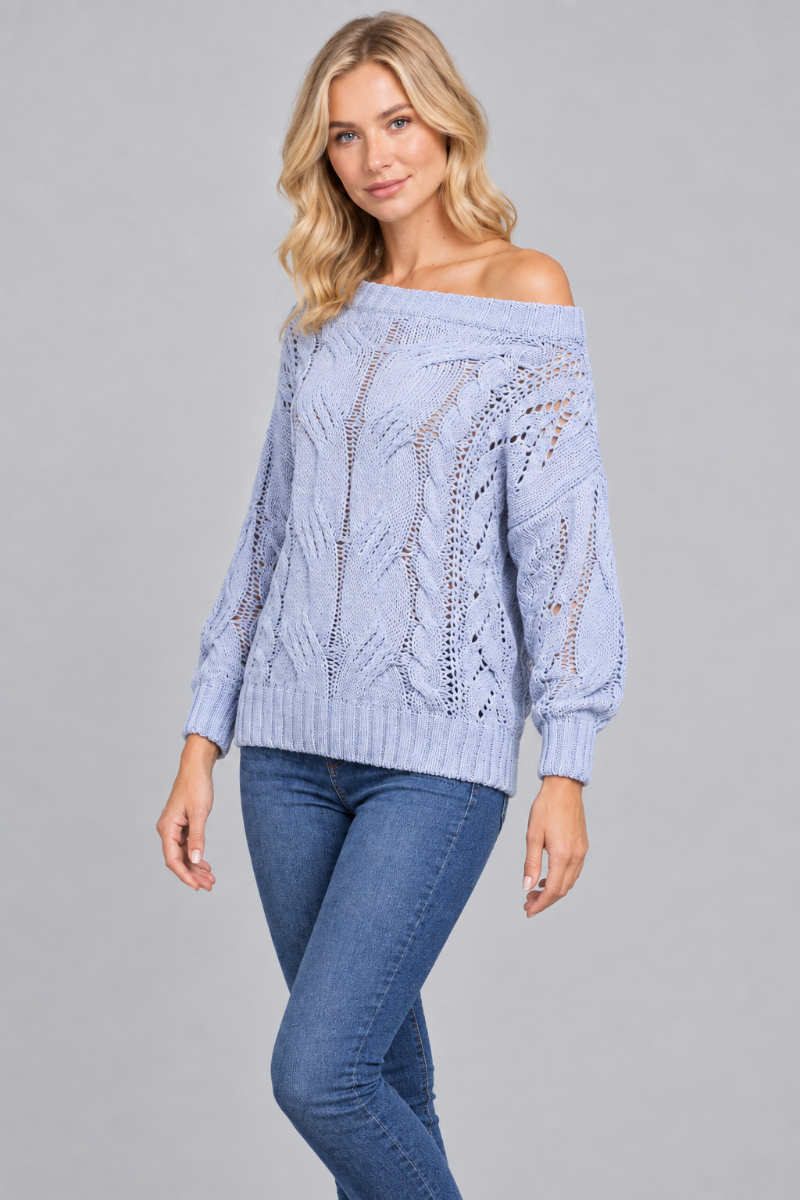 Three-quarter studio view of the blonde model wearing the pale-blue open-knit sweater and blue jeans