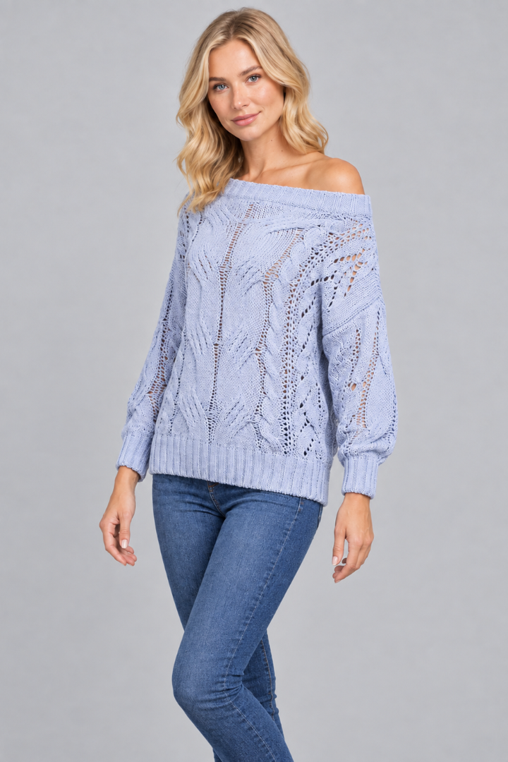 Three-quarter studio view of the blonde model wearing the pale-blue open-knit sweater and blue jeans