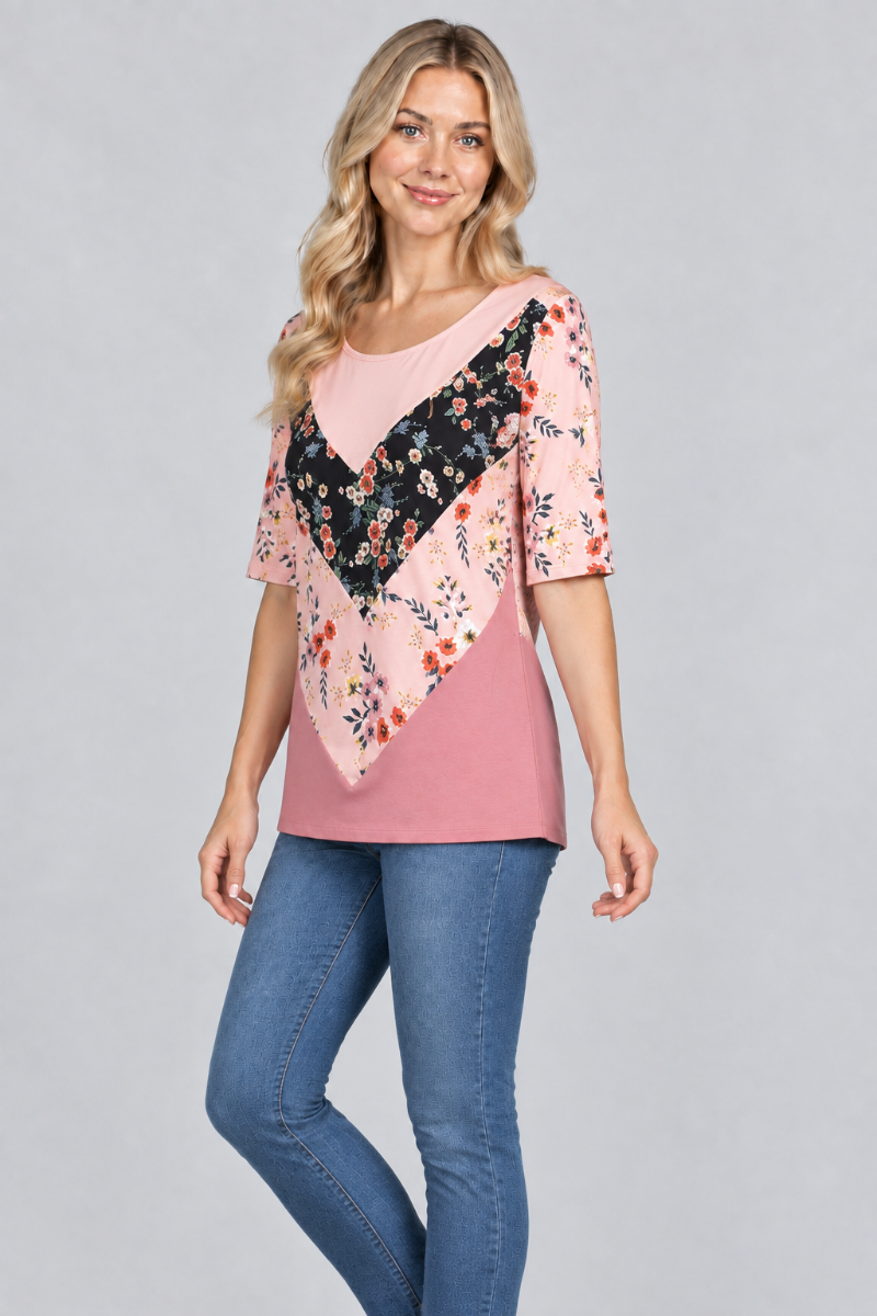 Three-quarter studio view of the blonde model wearing the pink floral color-block top and denim jeans