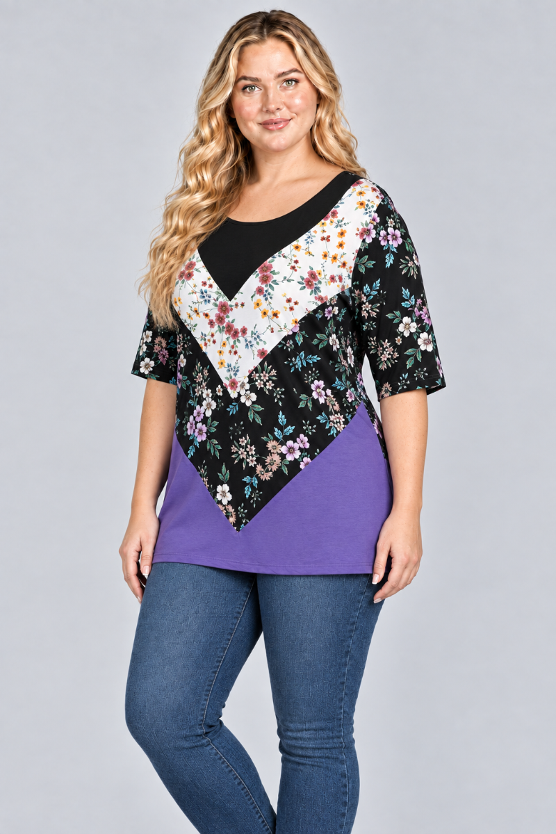 Three-quarter studio view of the blonde plus-size model wearing the black-and-purple floral color-block tunic