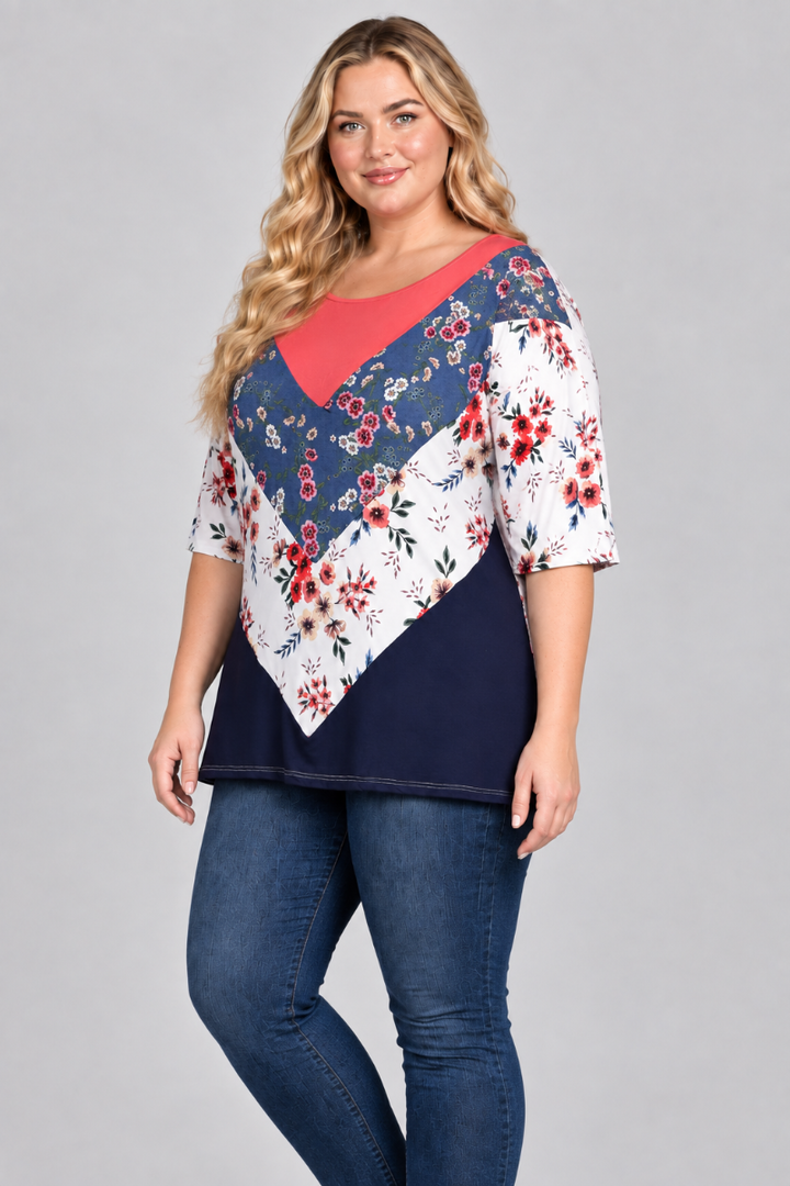 Three-quarter studio view of the blonde plus-size model wearing the floral color-block top and blue jeans