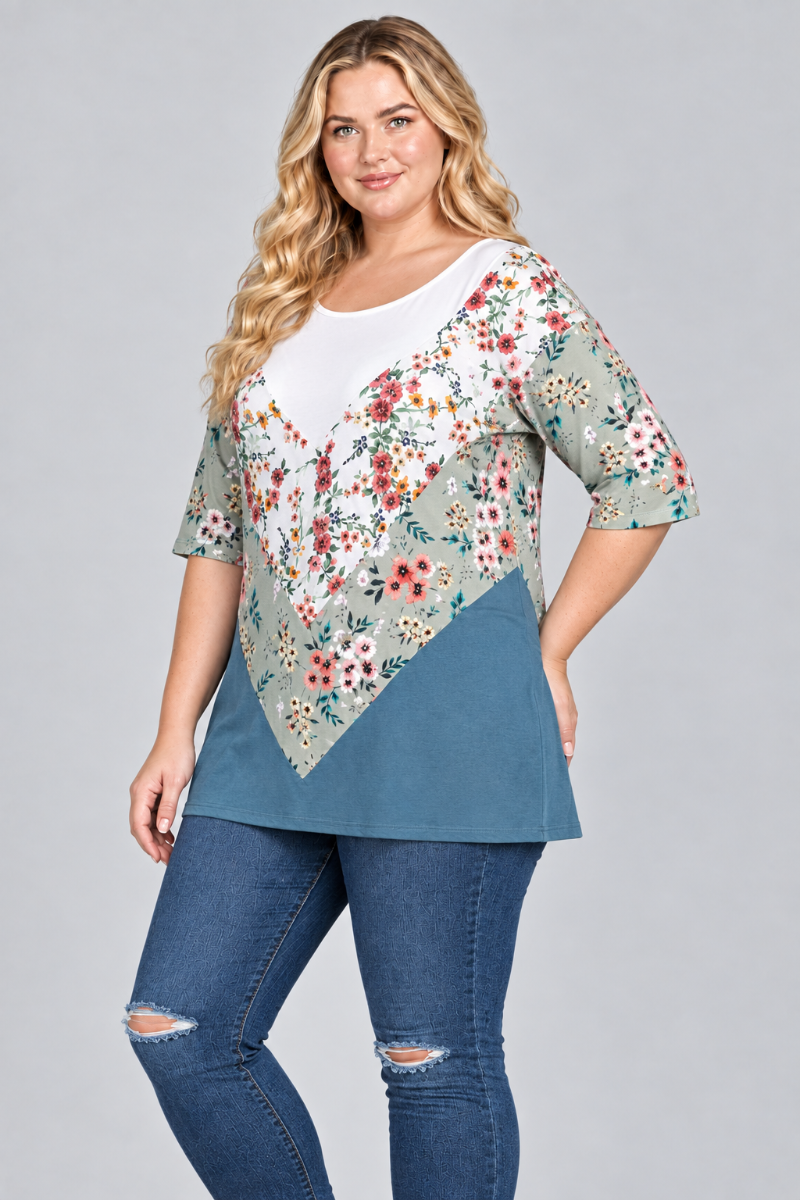 Three-quarter studio view of the blonde plus-size model wearing the white, sage floral, and teal tunic