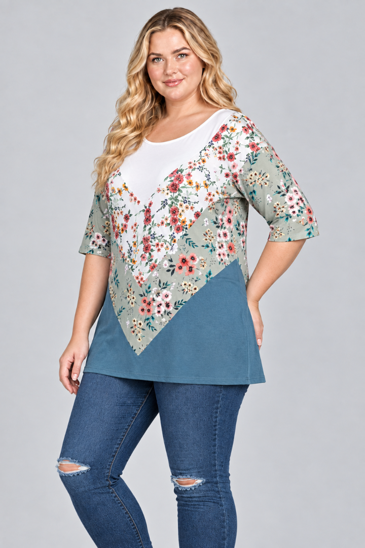 Three-quarter studio view of the blonde plus-size model wearing the white, sage floral, and teal tunic