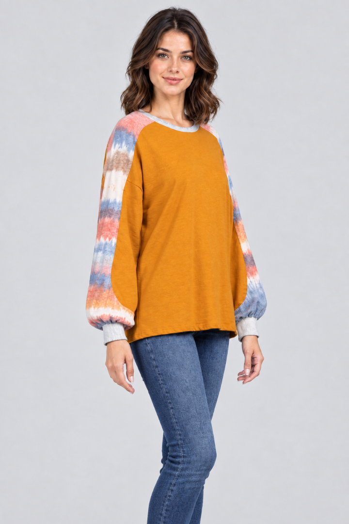 Three-quarter studio view of the mustard-orange top with tie-dye sleeves